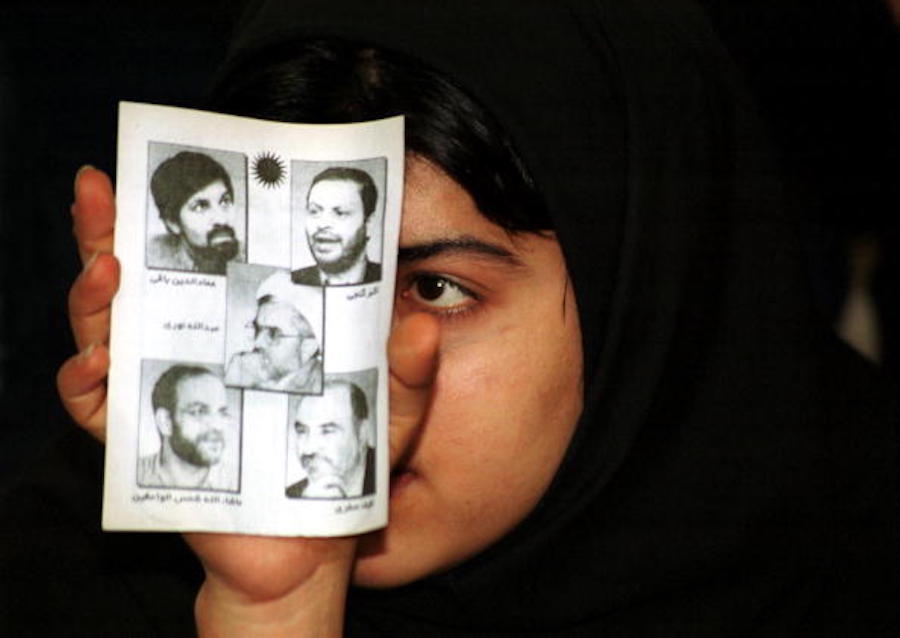 امرأة شابة إيرانية تحمل صور الصحافيين خلال تجمع في جامعة أمير كبير في طهران.